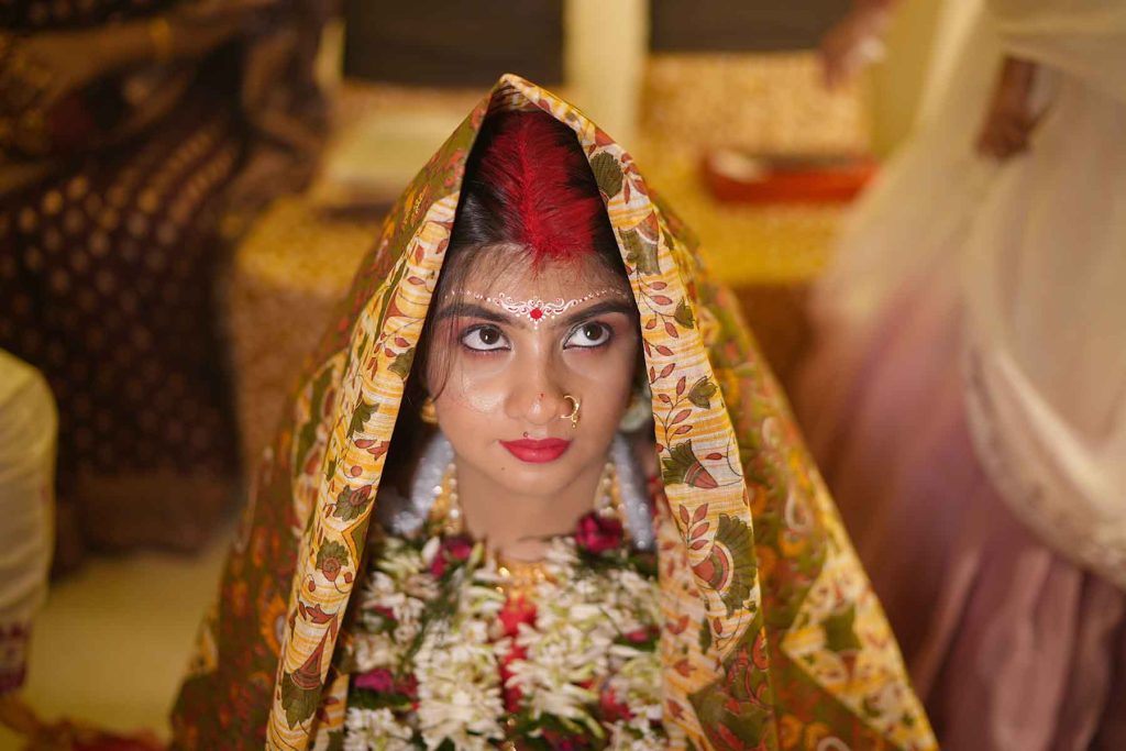 The exchange of flower garlands (Mala Badal) between the bride and groom during a traditional Bengali marriage ceremony.
