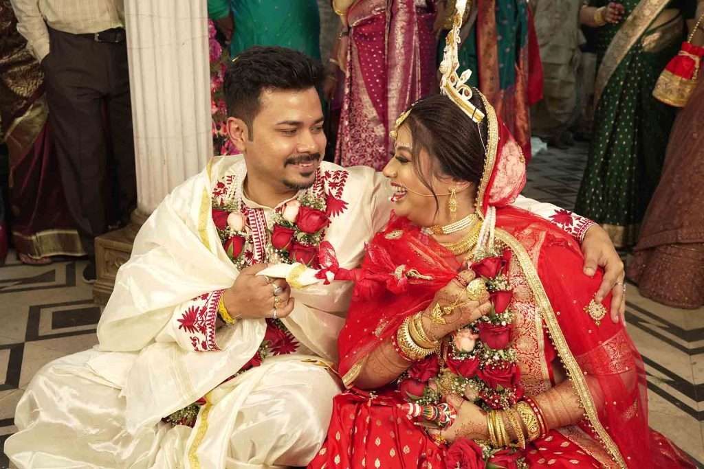 The iconic Shubho Drishti ritual where the Bengali bride removes the betel leaves to look at the groom for the first time.