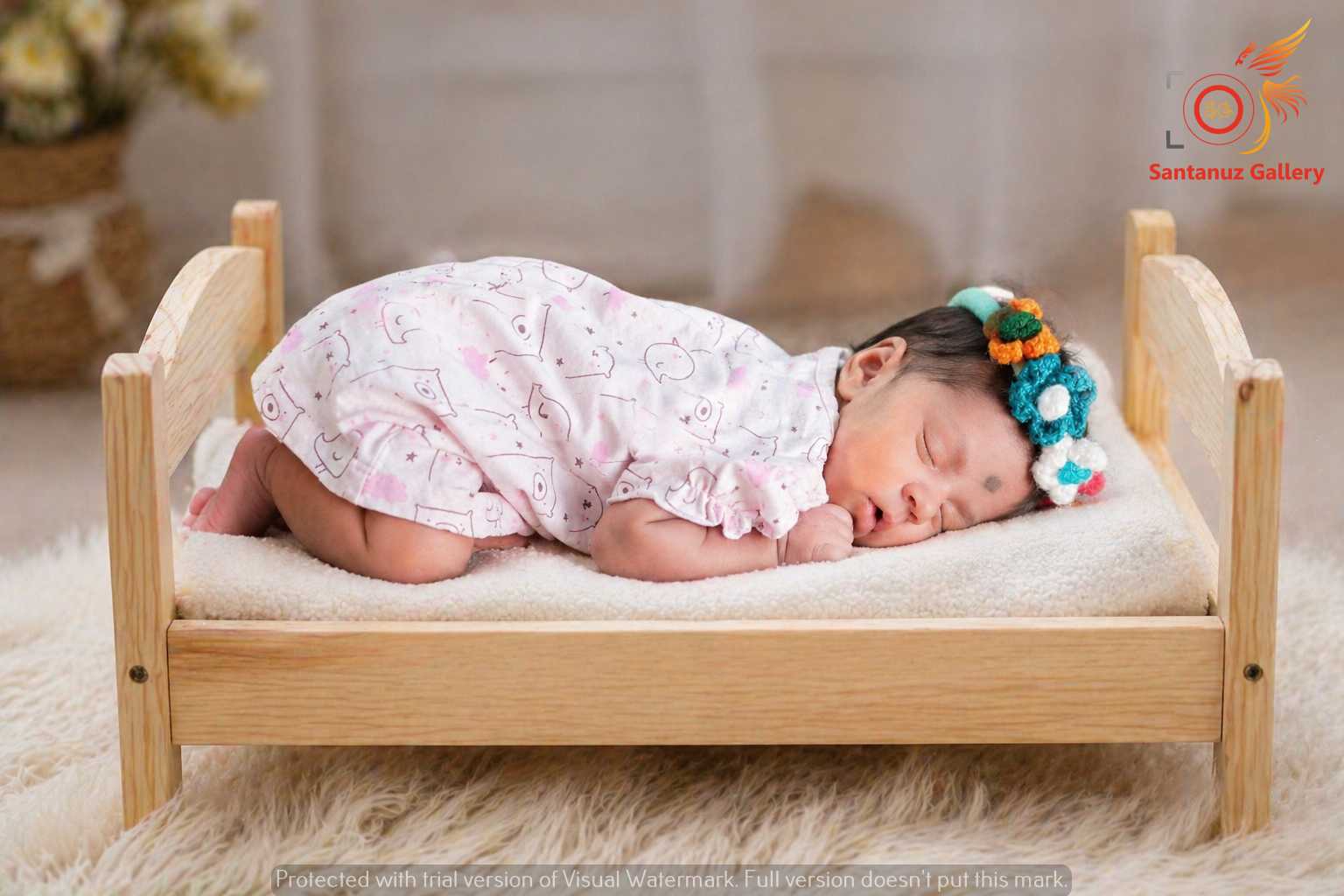 Newborn Photography Kolkata 19 A wide-eyed newborn baby with a soft, fuzzy brown bear-ear knitted hat, wide yawn, looking slightly past the camera, resting against a blurred striped blanket.