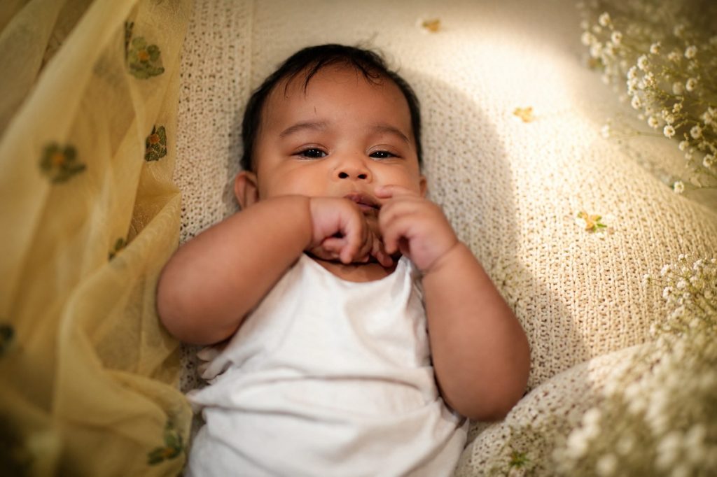 Adorable baby boy in traditional traditional silk ethnic wear posing for an Annaprashan photoshoot at home with brass utensils.